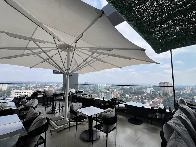 A calm rooftop café in East Africa overlooking Nairobi’s skyline, with soft afternoon light and empty wooden tables.
