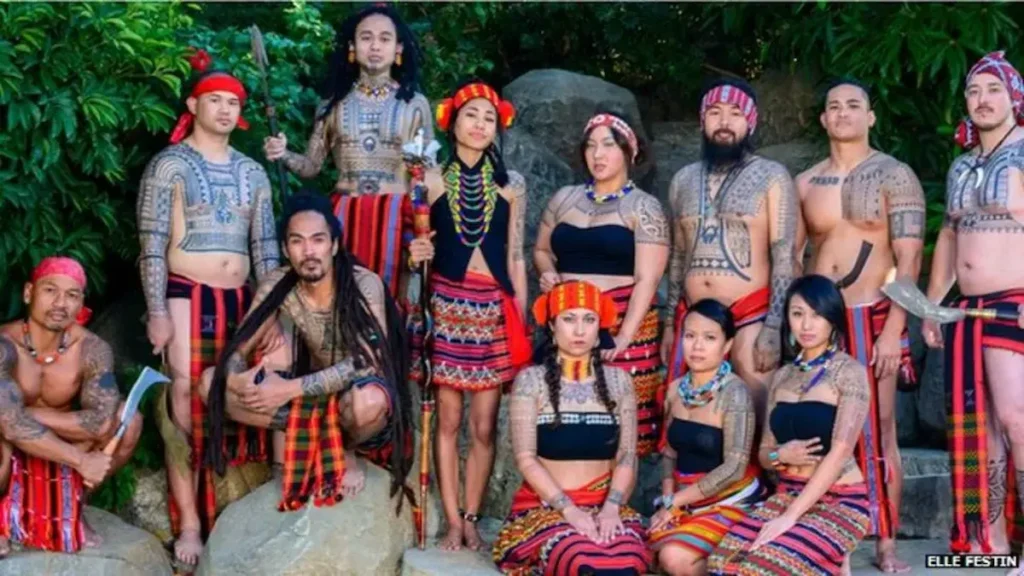 Group of people wearing traditional costumes and showing tribal tattoos alongside modern tattoo styles