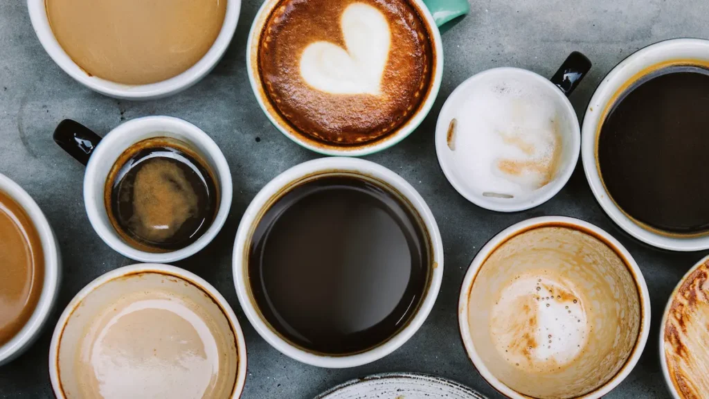 Flat lay of different coffee cups showing lattes, cold brews, and espresso on a table, representing diverse coffee tastes across generations.