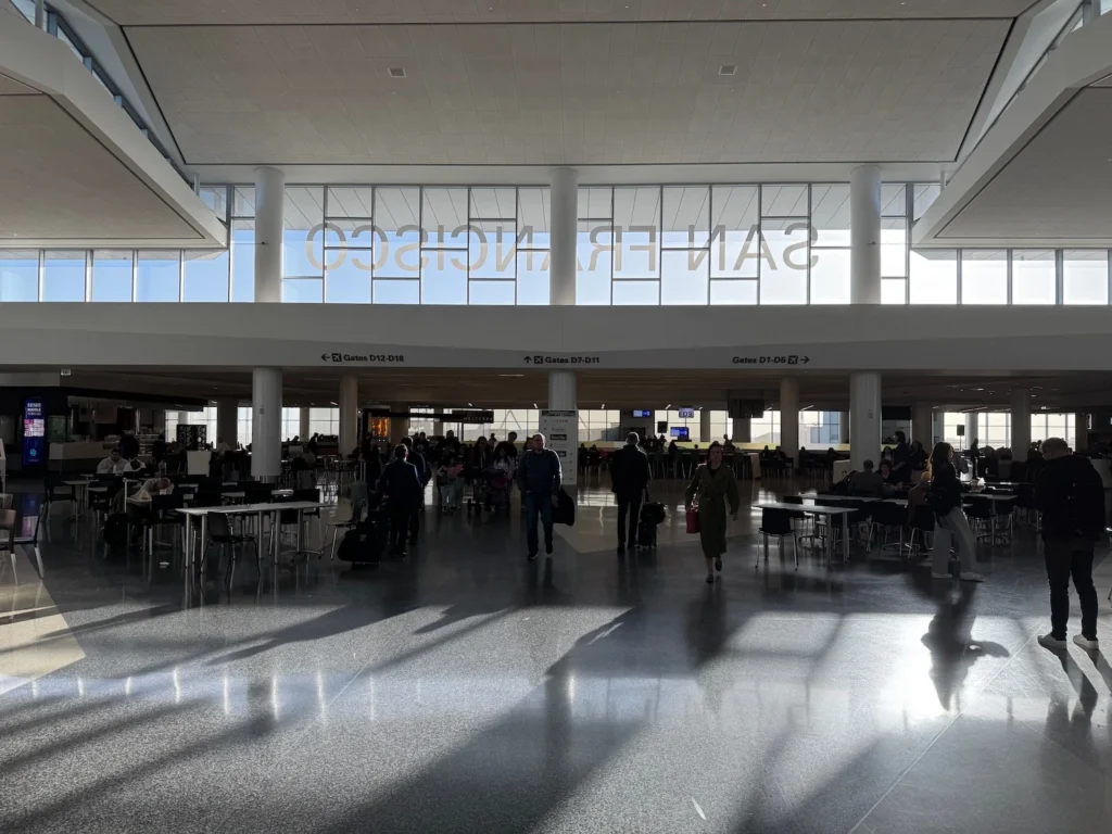 A sunlit terminal where travelers pause between gates, coffee cups in hand and quiet steps echoing through the airy space.