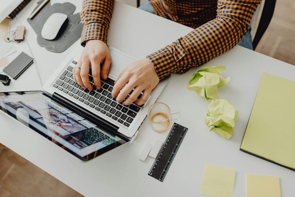 Flat lay of a travel creator planning Pinterest boards with laptop, maps, and coffee.